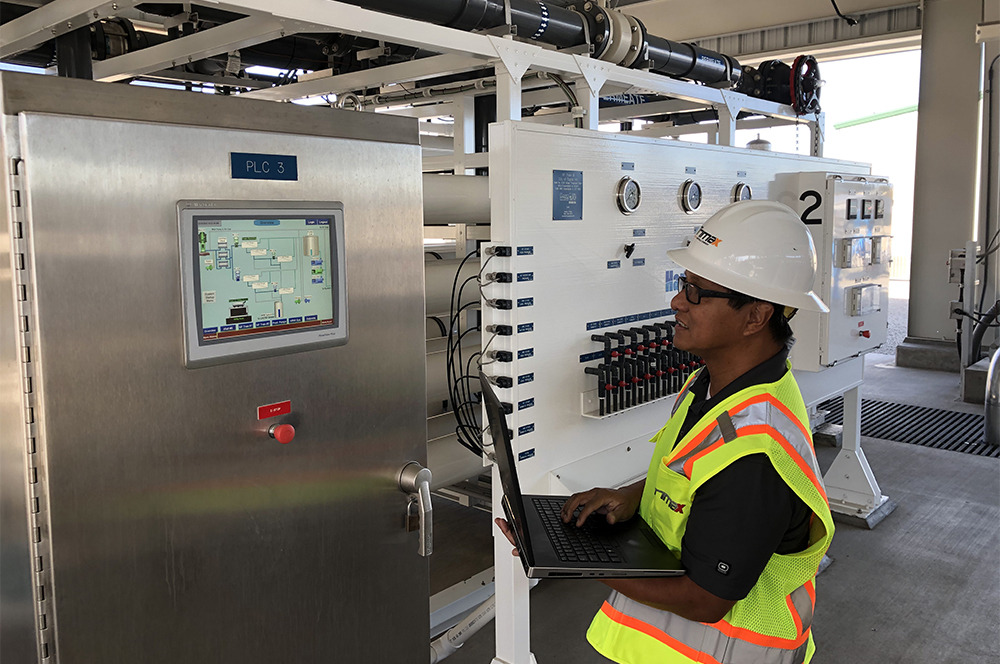 Trimax technician viewing computer and operator interface at a plant